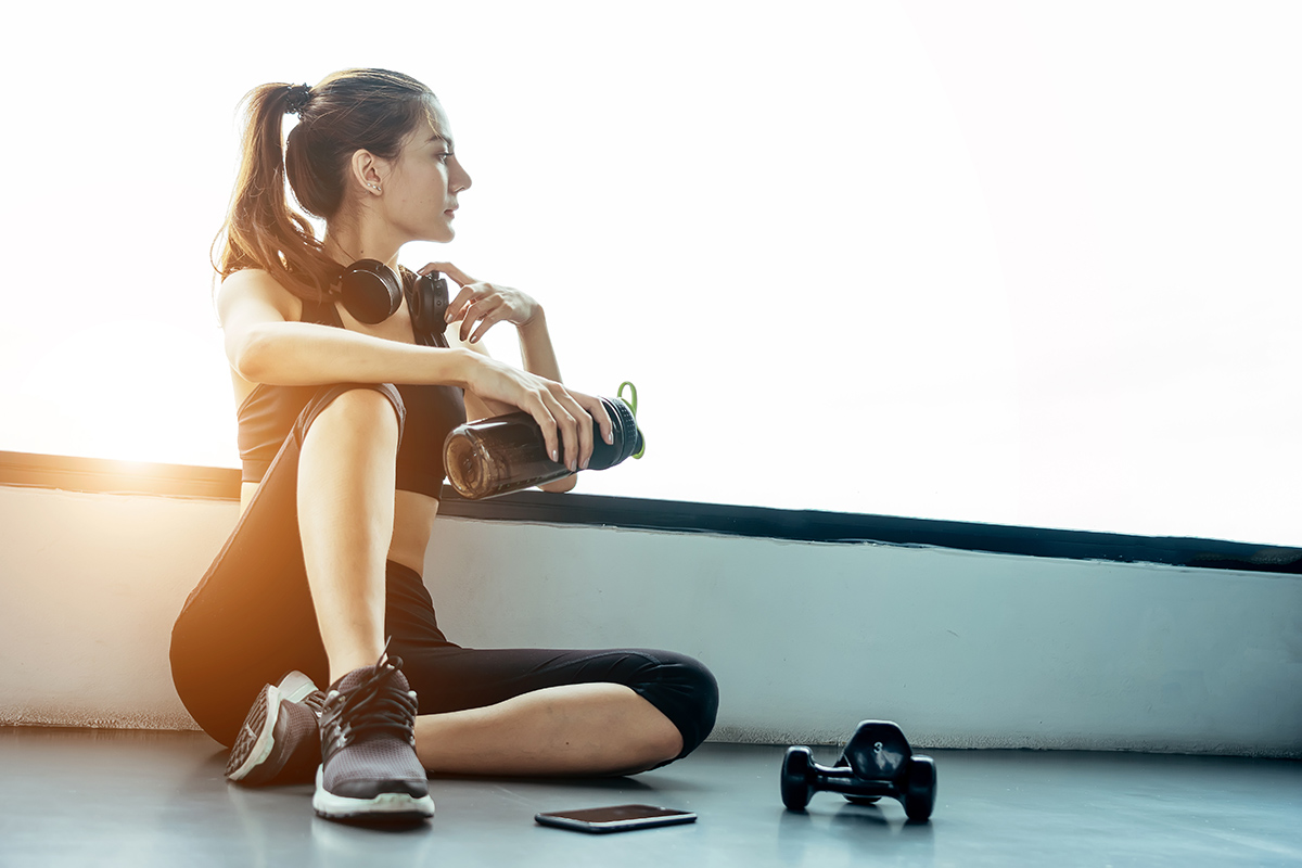 Asian woman exercising in the gym, Young woman workout in fitness for her healthy and office girl lifestyle. She using smart phone to check an email or listening music.