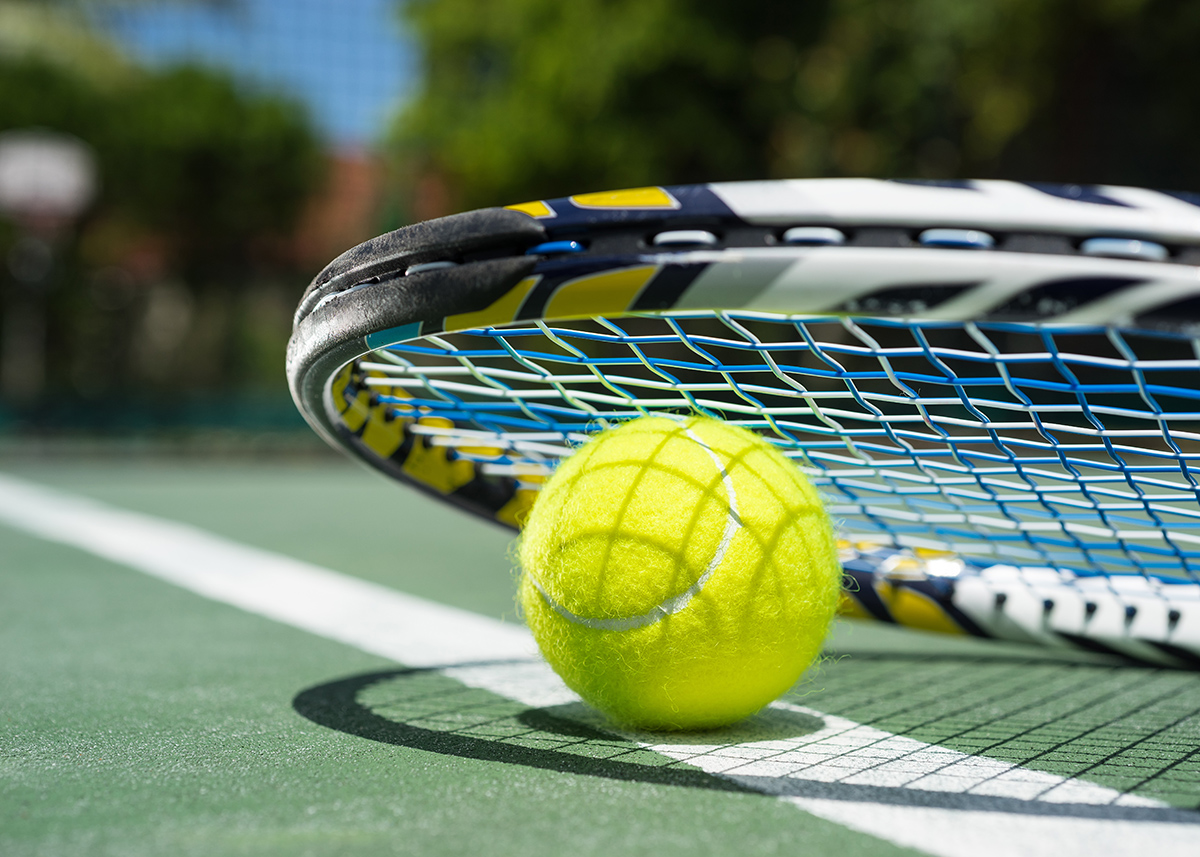 Close up view of tennis racket and balls on tennis court